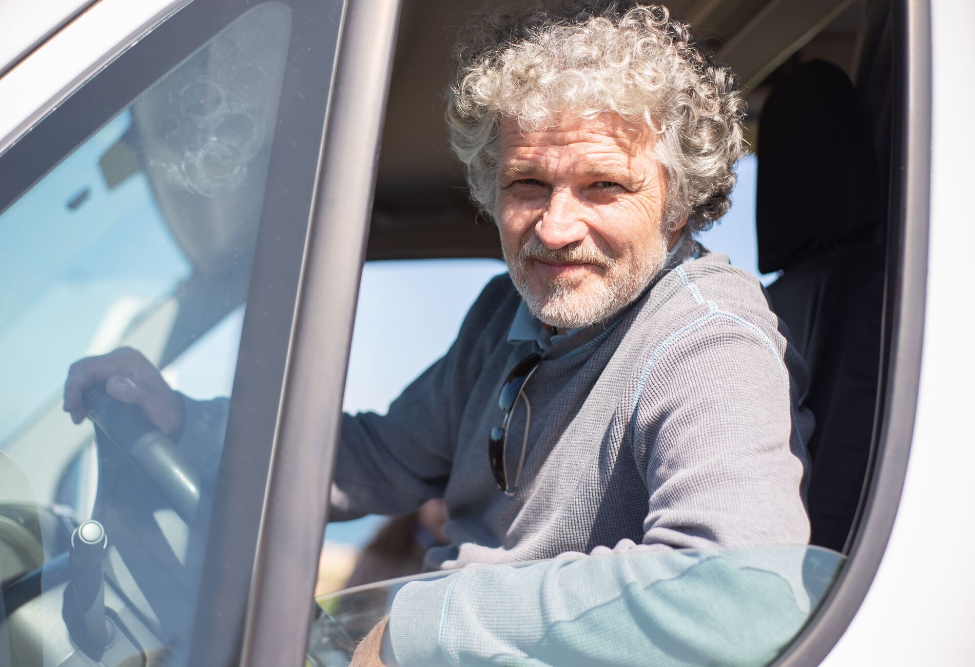 Lachende chauffeur in het raam van een bus